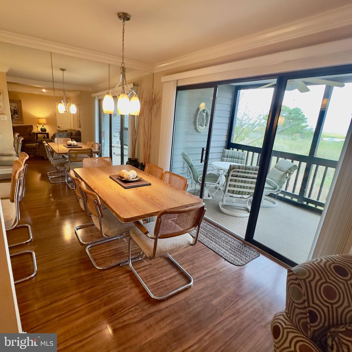 119 Old Landing Road, Unit E203 Ocean City, MD 21842 - Photo 9 of 45 a dining room with wooden floor a chandelier a glass table and chairs
