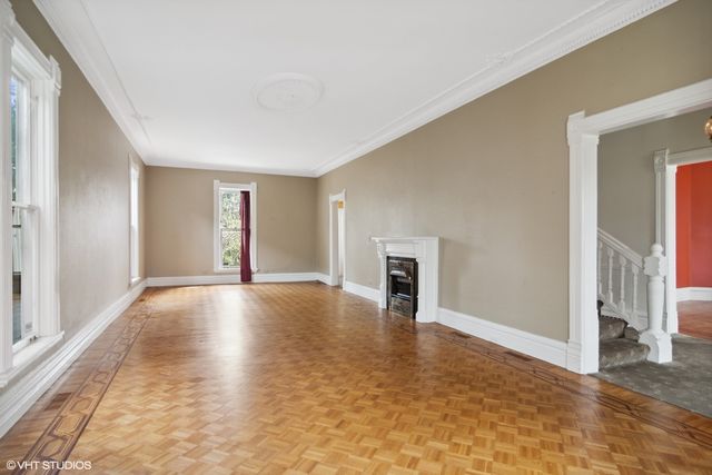 a view of empty room with wooden floor and fireplace
