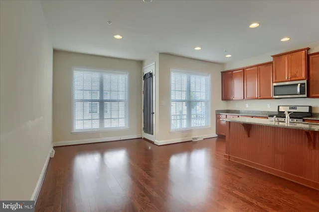 a view of kitchen with granite countertop wooden floors wooden cabinets a sink and a window