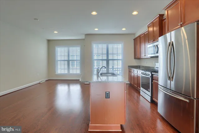 a kitchen with stainless steel appliances granite countertop a refrigerator a sink dishwasher a stove and a refrigerator with wooden floor