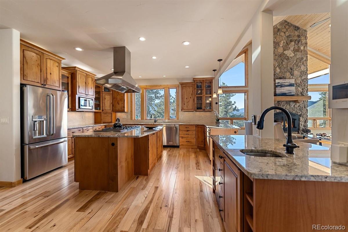 2848 Quartz Ridge Road Evergreen, CO 80439 - Photo 8 of 40 a kitchen with stainless steel appliances granite countertop a refrigerator a sink dishwasher a stove and a dining table with wooden floor