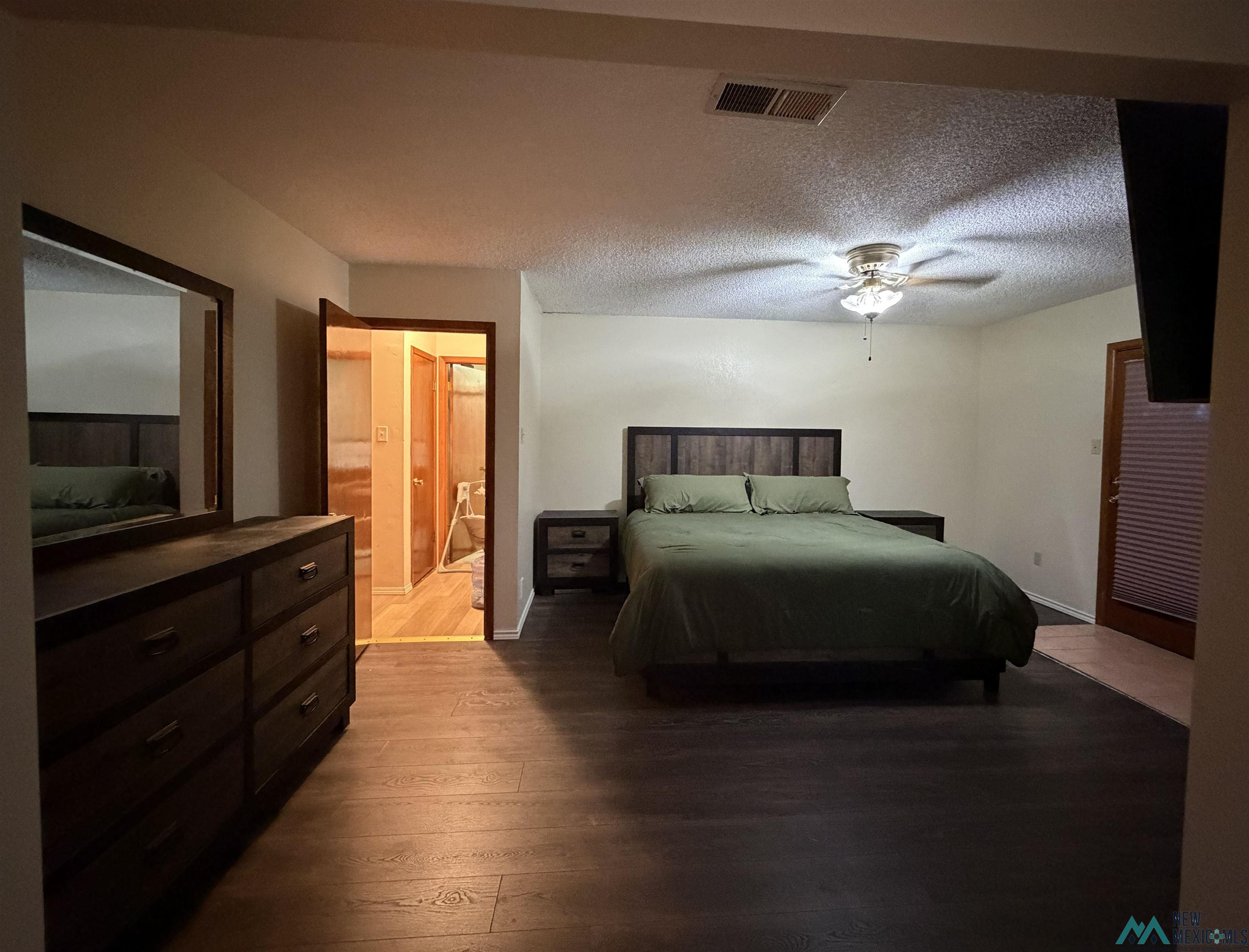 2001 East Derrick Road Carlsbad, NM 88220 - Photo 69 of 84 Bedroom with a textured ceiling, connected bathroom, dark wood-type flooring, and a ceiling fan