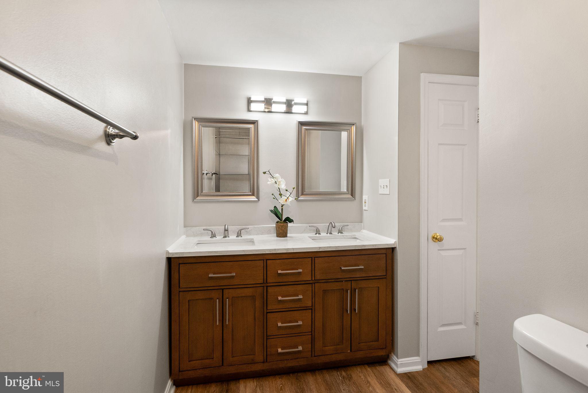 1700 Quietree Drive Reston, VA 20194 - Photo 49 of 76 a bathroom with a double vanity sink and mirror with toilet