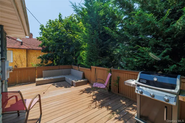a view of a patio with table and chairs with barbeque grill and wooden fence