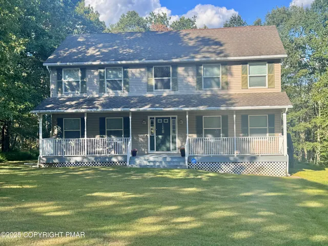 a front view of a house with swimming pool and large trees