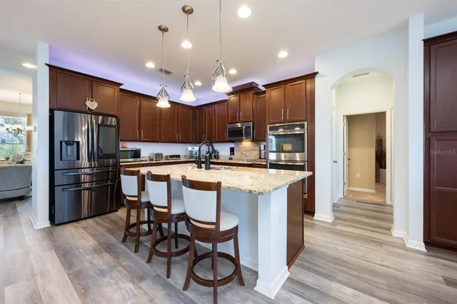 a kitchen with kitchen island a refrigerator a stove a sink and a oven with wooden floor