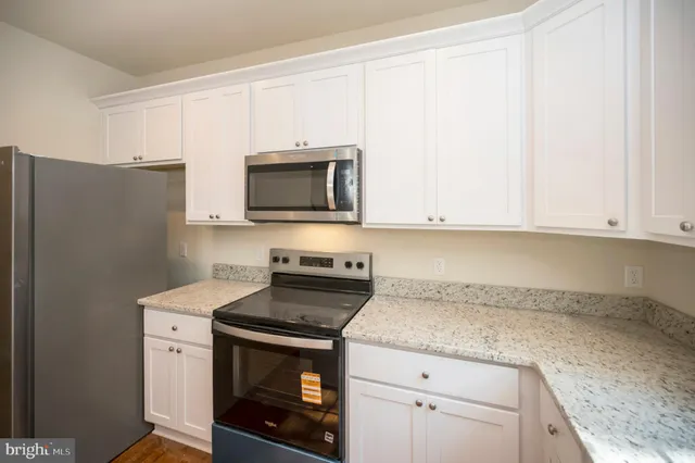 a kitchen with granite countertop white cabinets and window