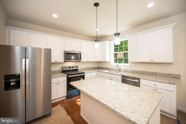 a kitchen with stainless steel appliances granite countertop a sink a stove a counter space and a window