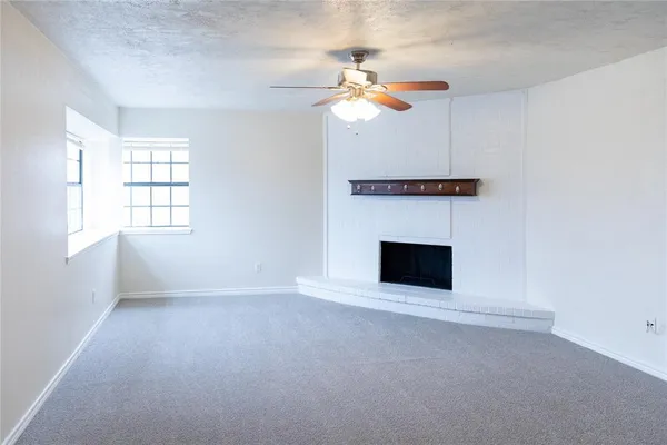 an empty room with windows and fireplace