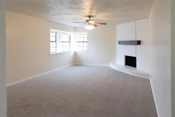 an empty room with windows and fireplace