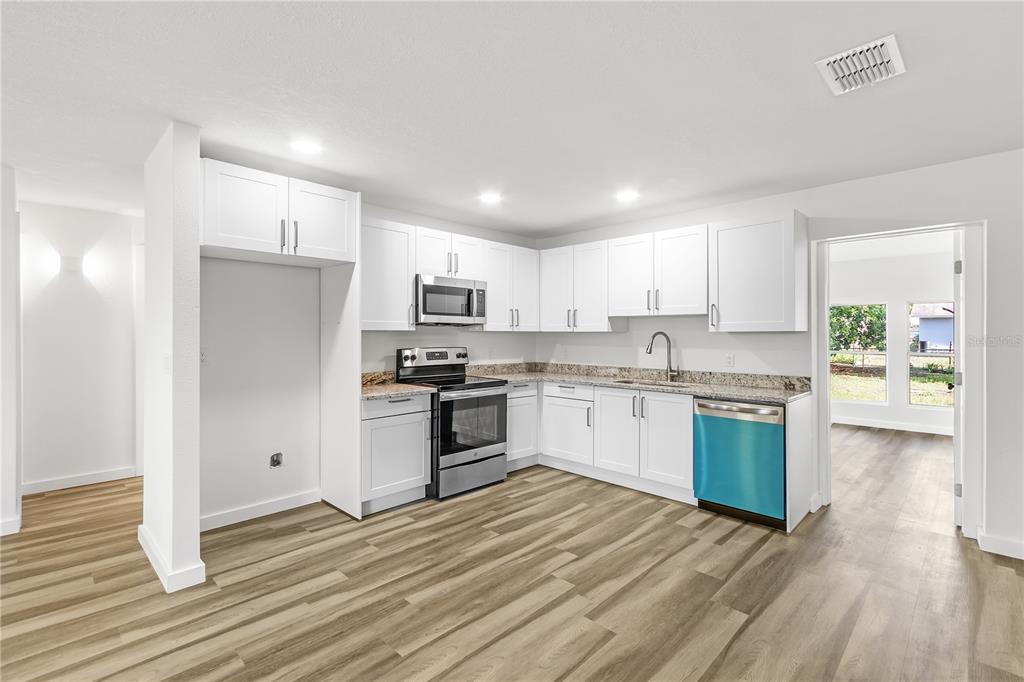 426 Bascom Court Polk City, FL 33868 - Photo 6 of 33 a kitchen with granite countertop white cabinets and stainless steel appliances