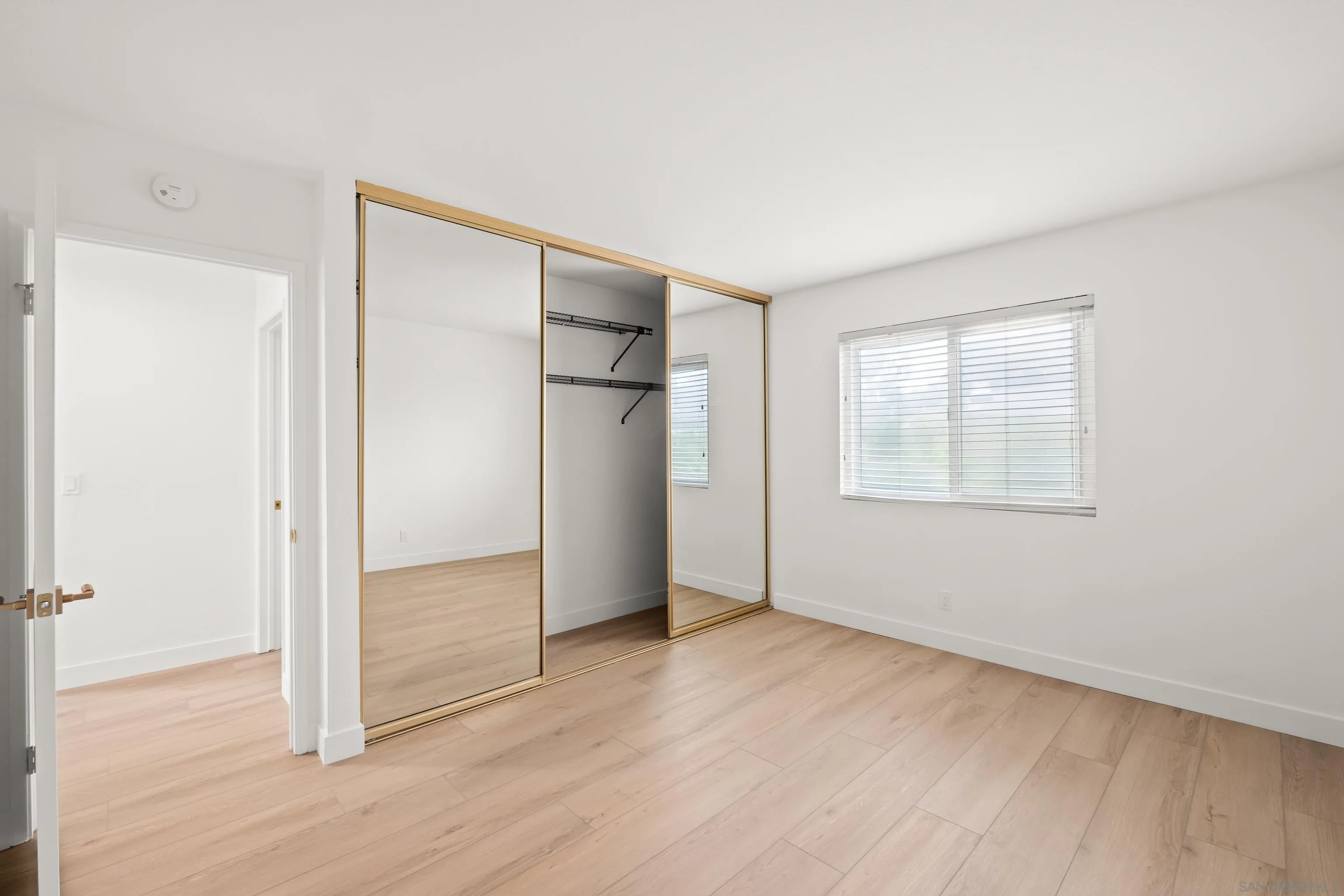 11478 Madera Rosa Way San Diego, CA 92124 - Photo 24 of 54 an empty room with wooden floor and windows