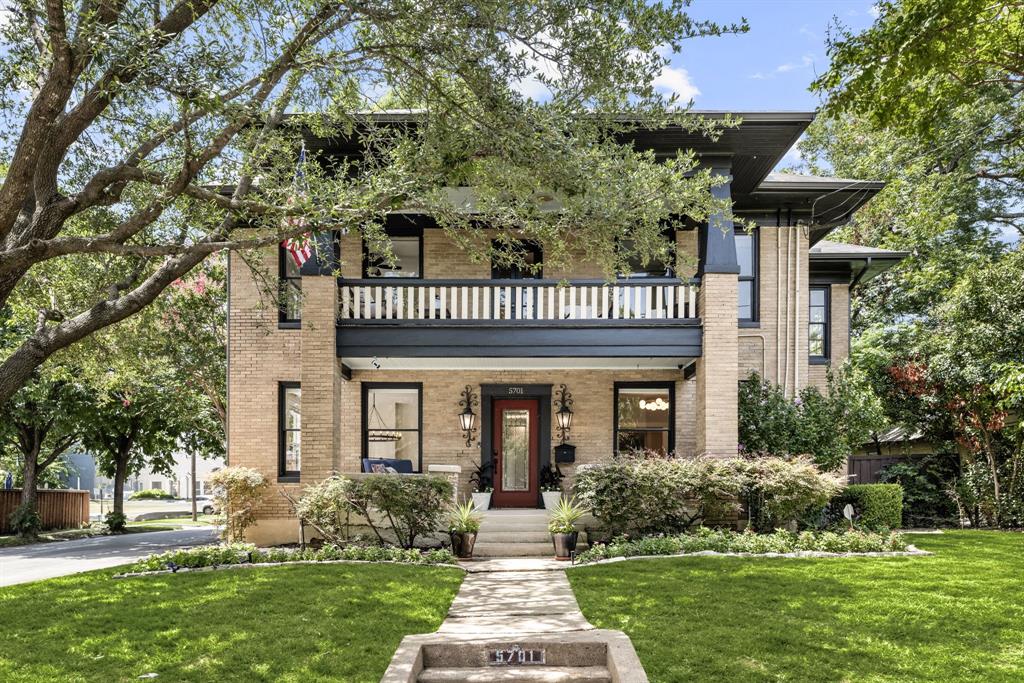 View of front of house with a balcony, a front lawn, and brick siding