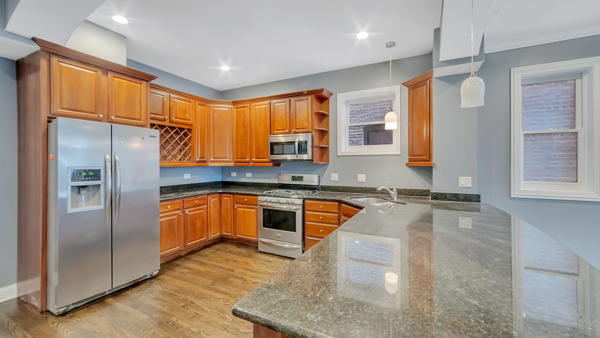 2417 West Fillmore Street, Unit 1 Chicago, IL 60612 - Photo 6 of 19 a kitchen with stainless steel appliances granite countertop a refrigerator a stove and a sink with wooden floor