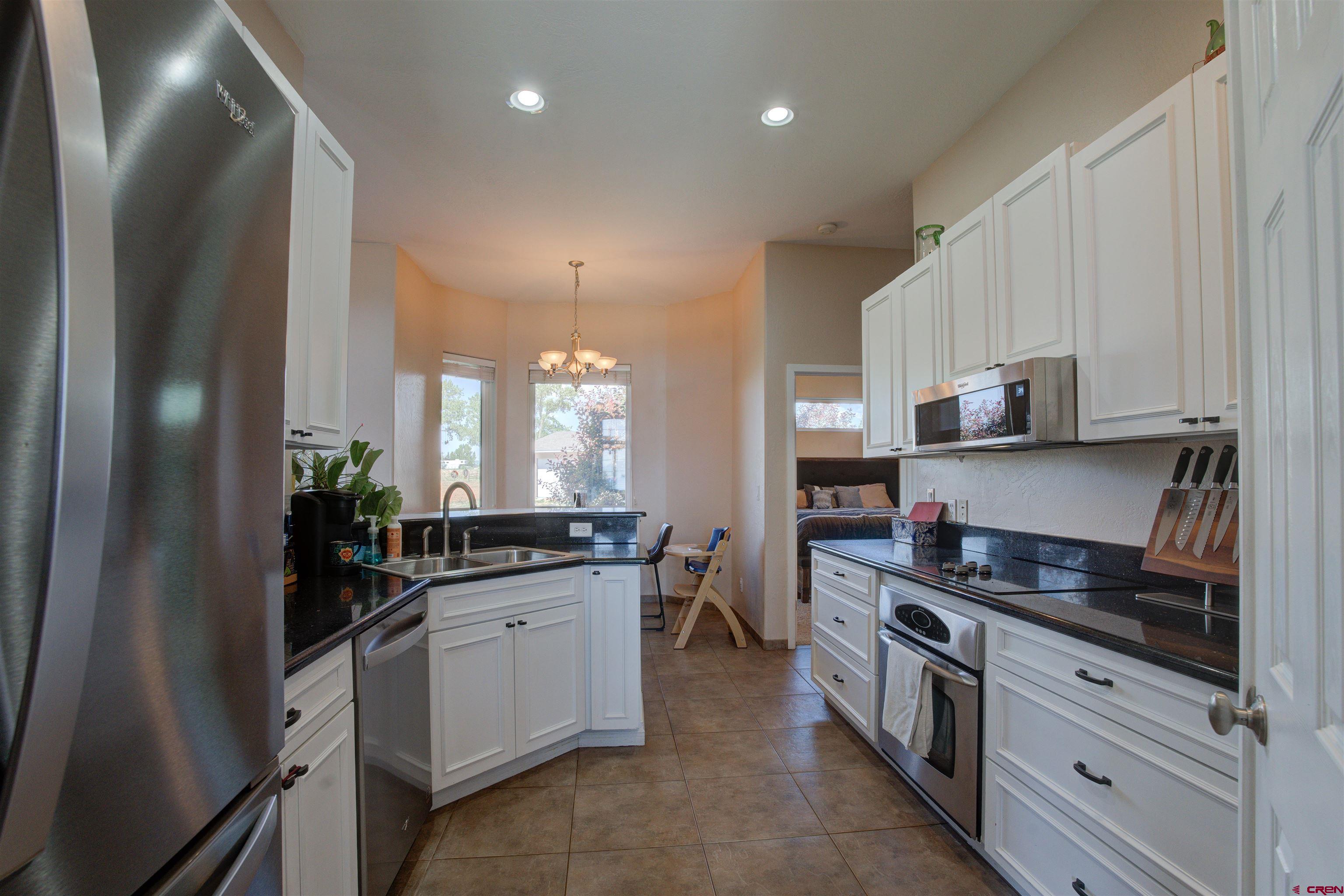 12868 Road 24.4 Loop Cortez, CO 81321 - Photo 8 of 28 a kitchen with granite countertop a stove a sink and a refrigerator