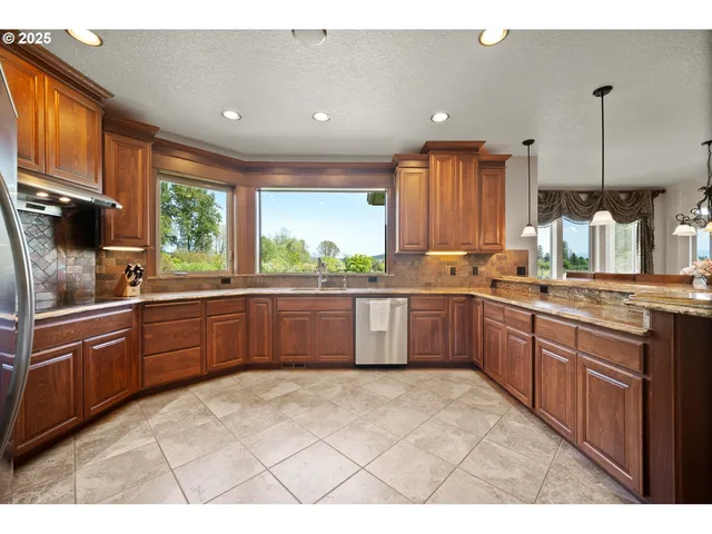 a kitchen with stainless steel appliances kitchen island granite countertop a sink counter space cabinets and a large window