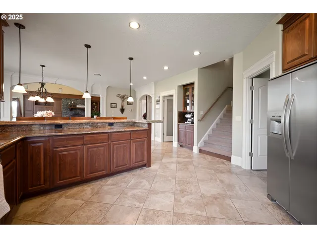 a large kitchen with stainless steel appliances kitchen island granite countertop a refrigerator and a sink