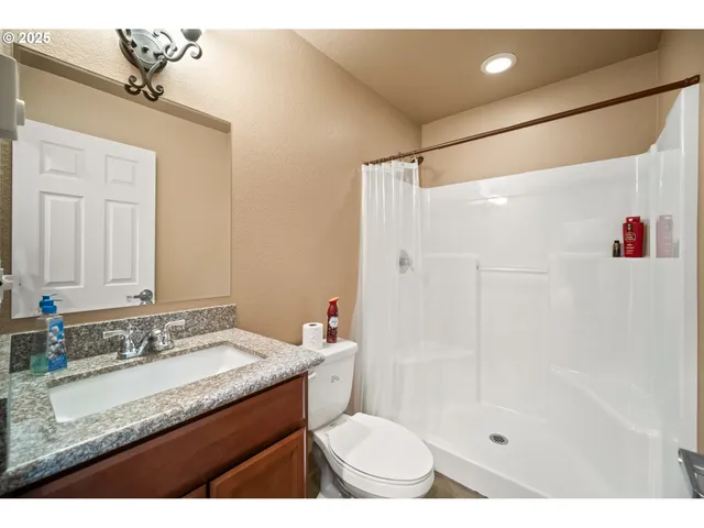 a bathroom with a granite countertop sink a toilet and shower