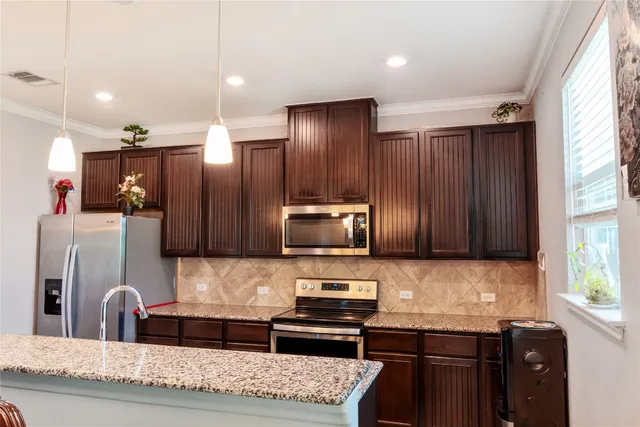 a kitchen with stainless steel appliances granite countertop a refrigerator and a stove top oven