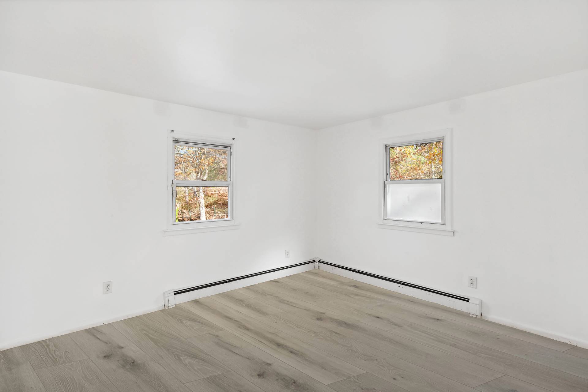 16 Peconic Road Hampton Bays, NY 11946 - Photo 6 of 17 an empty room with a wooden floor and a window