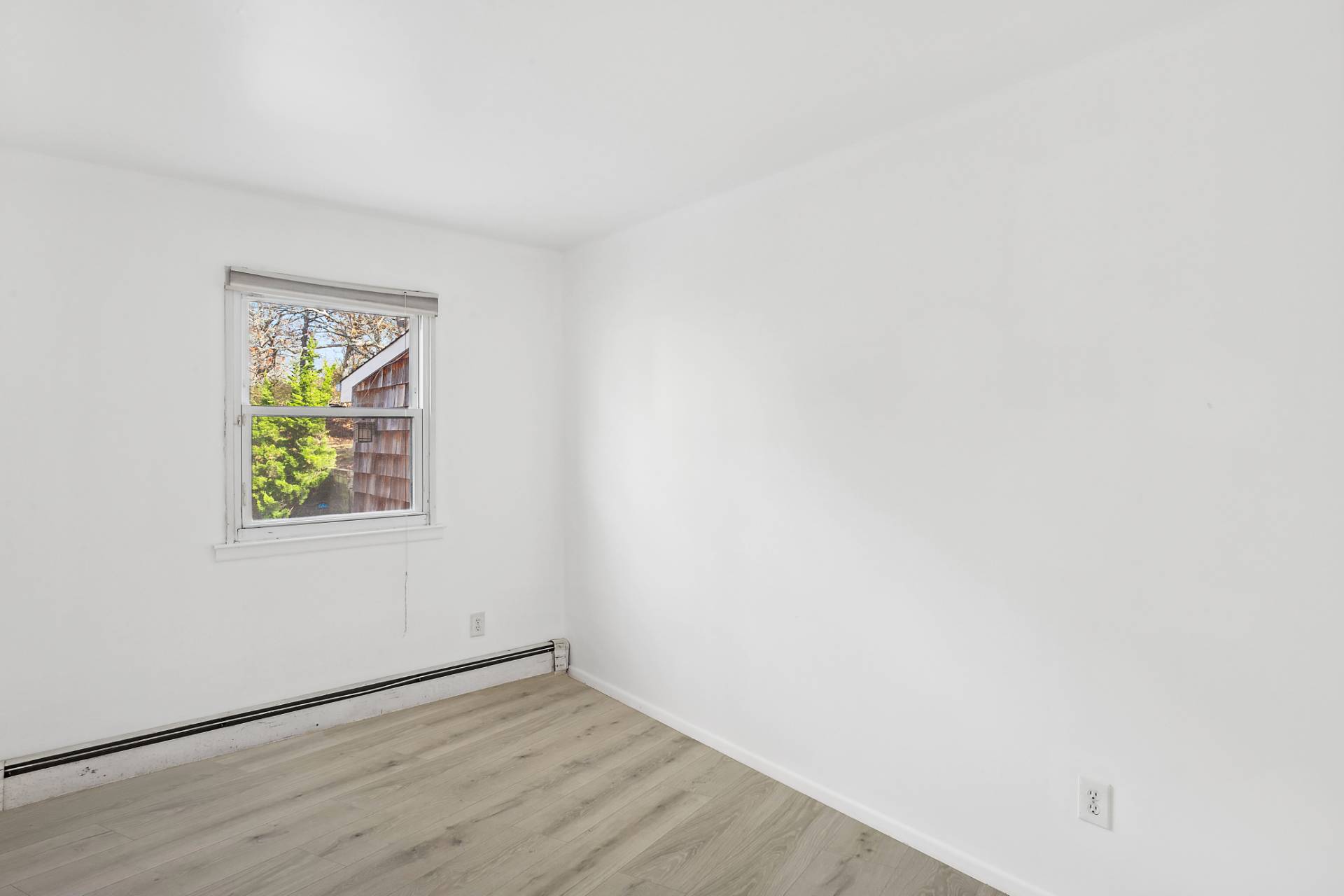 16 Peconic Road Hampton Bays, NY 11946 - Photo 10 of 17 an empty room with wooden floor and window