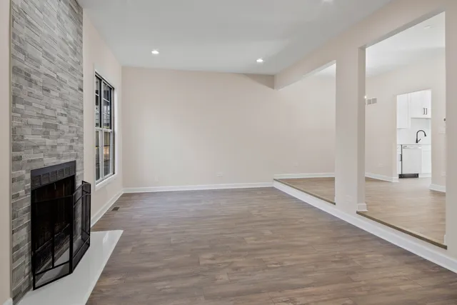 an empty room with wooden floor a fireplace and windows