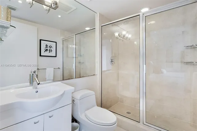a bathroom with a shower sink vanity mirror and toilet
