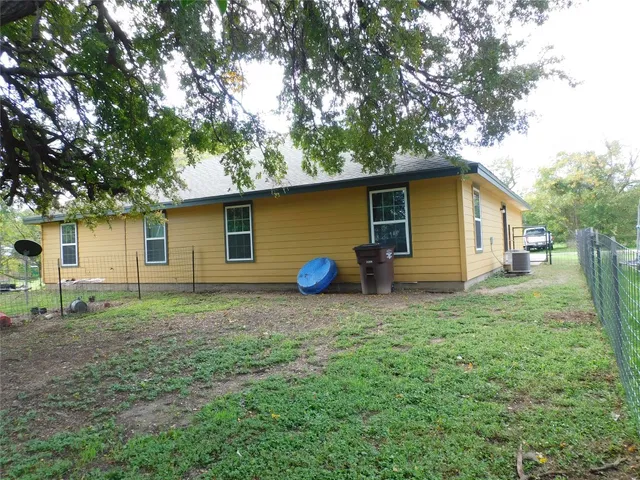a view of a backyard with plants and large tree