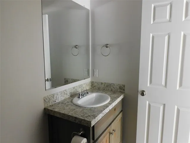 a bathroom with a granite countertop sink and a mirror