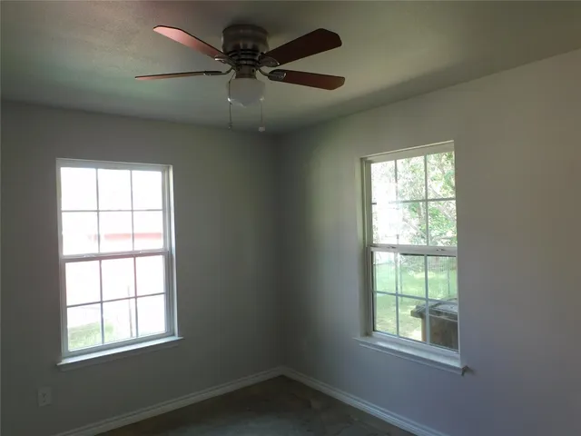 an empty room with a window and a fan