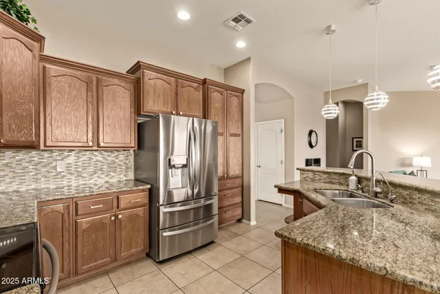 a kitchen with stainless steel appliances granite countertop a sink refrigerator and cabinets