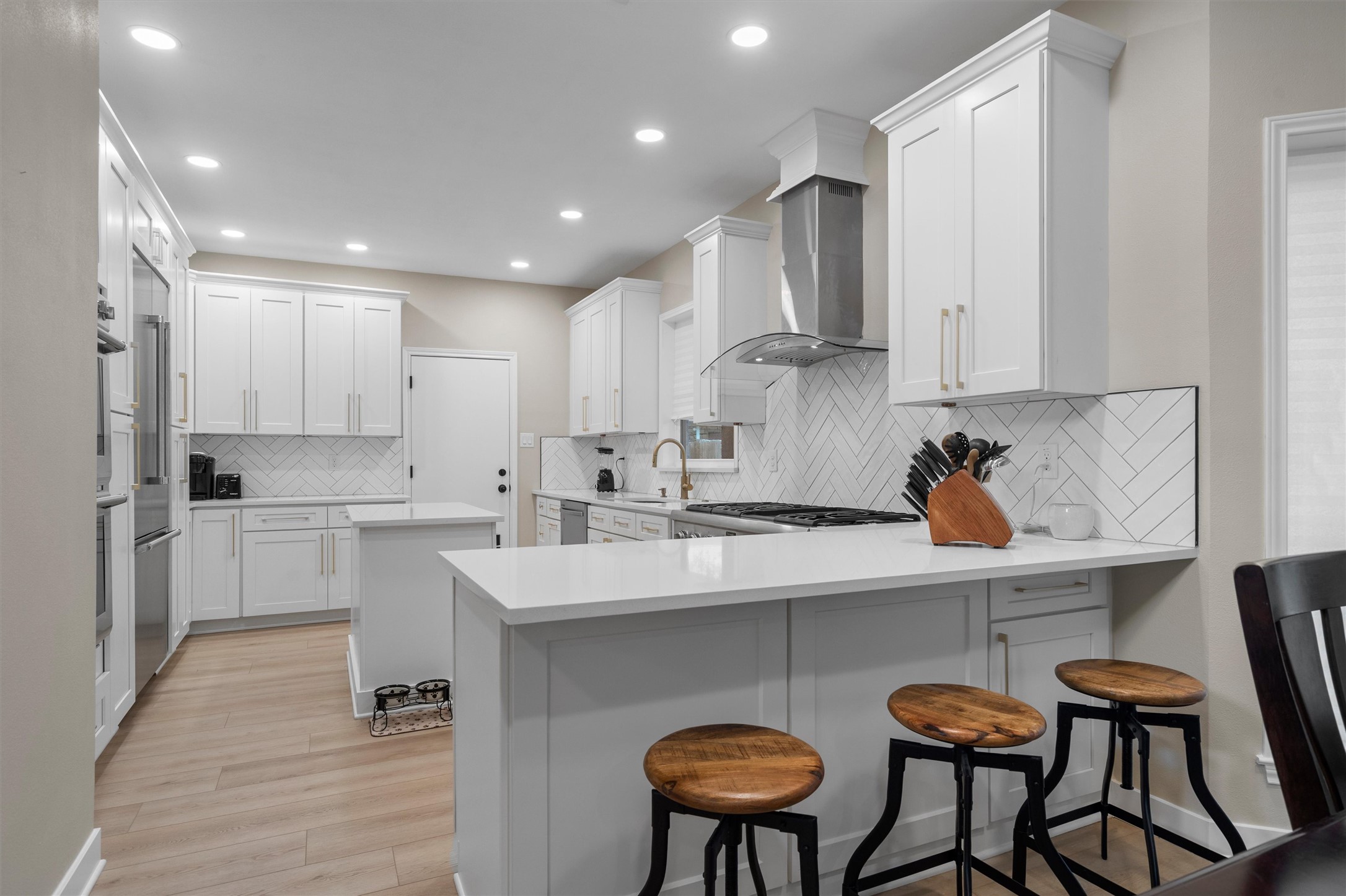 307 Hurst Creek Road Austin, TX 78734 - Photo 9 of 40 Contemporary kitchen featuring white shaker cabinetry, quartz countertops, a herringbone tile backsplash, and stainless steel appliances