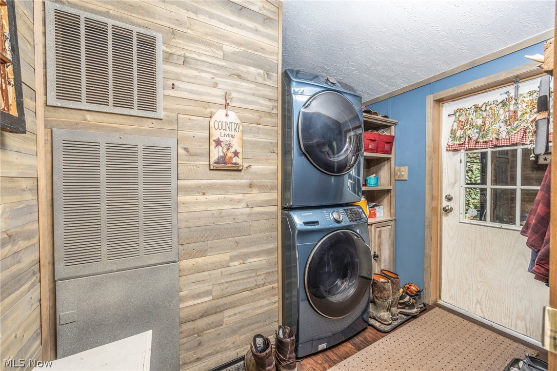 1788 Rosenbush Road Newport, OH 45768 - Photo 15 of 43 Laundry area featuring stacked appliances, wood-finish flooring, and shiplap wall treatment