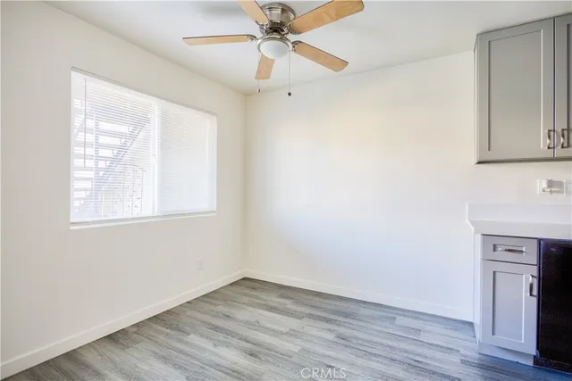 an empty room with wooden floor ceiling fan and windows