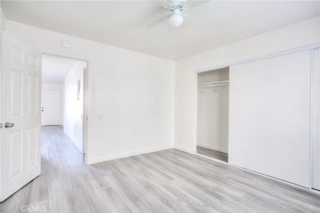 an empty room with wooden floor and fan