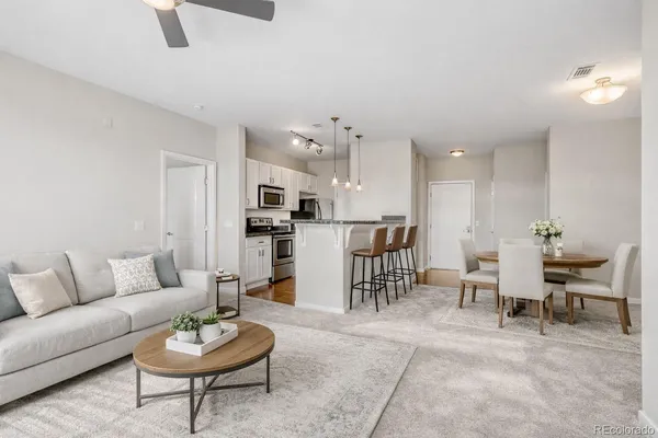 a living room with furniture kitchen view and a wooden floor