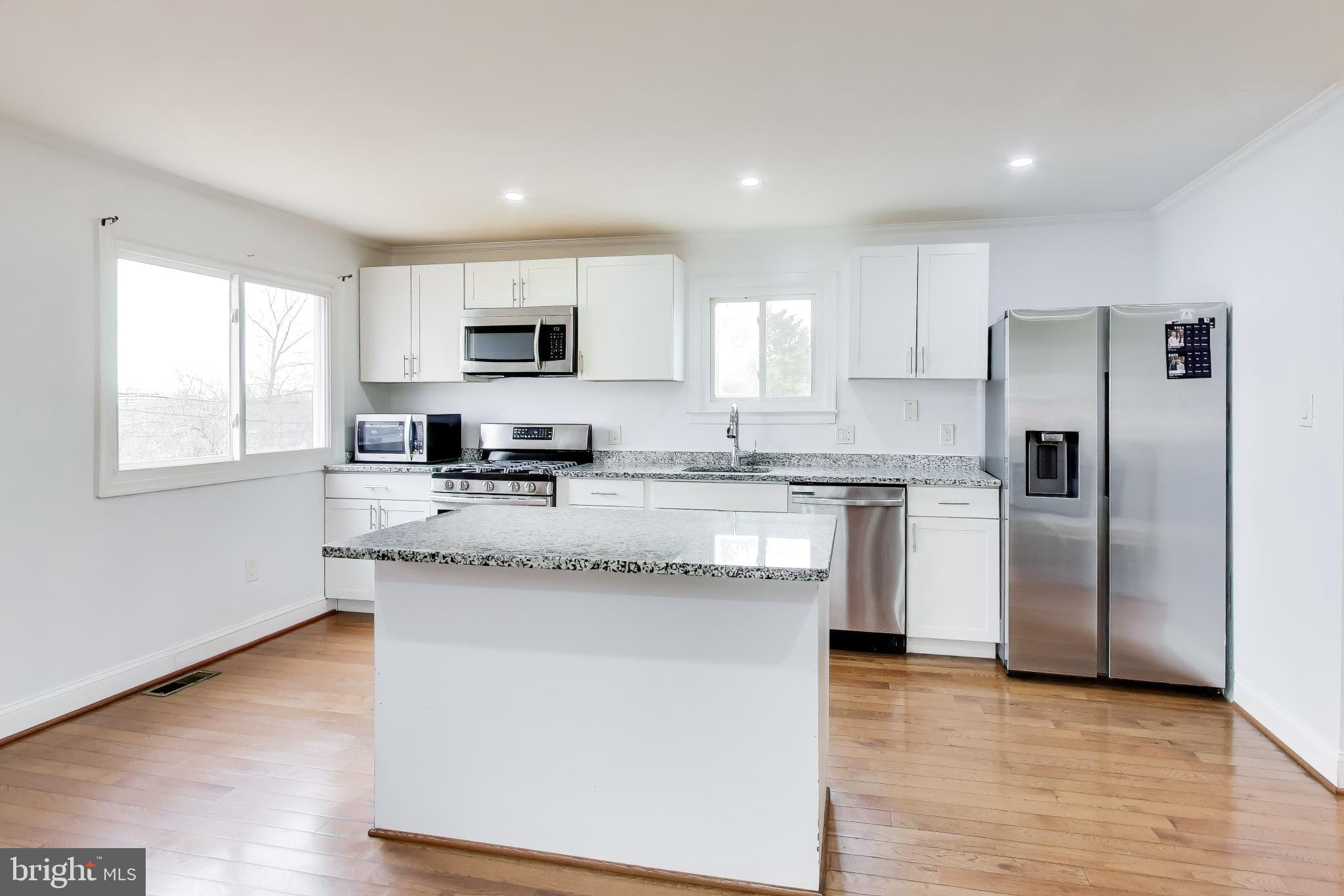 1028 Ward Street Laurel, MD 20707 - Photo 10 of 39 a kitchen with granite countertop a refrigerator a sink dishwasher a stove and white cabinets with wooden floor