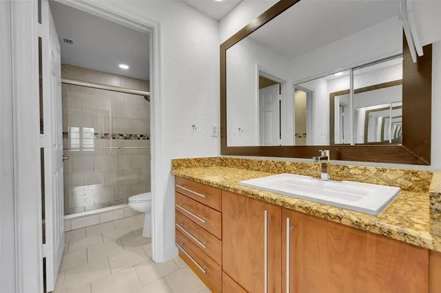 a bathroom with a granite countertop sink a toilet and a shower