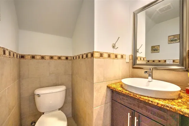 a bathroom with a granite countertop sink mirror vanity and toilet