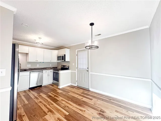 a kitchen with a refrigerator and white cabinets