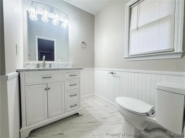 a bathroom with a toilet a sink a vanity and mirror