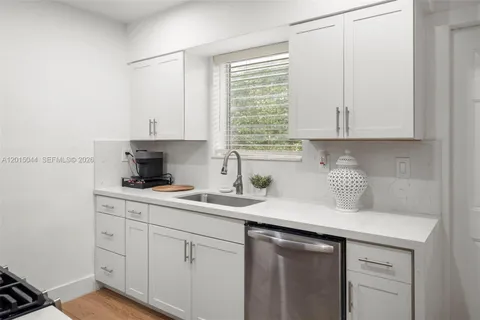 a kitchen with stainless steel appliances granite countertop a sink a stove and white cabinets