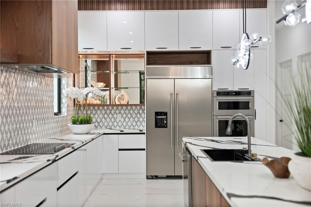 135 7th Street North Naples, FL 34102 - Photo 10 of 50 The stunning chef’s kitchen is equipped with quartz countertops, sleek white cabinetry, warm wood accents, and an oversized walk-in pantry.