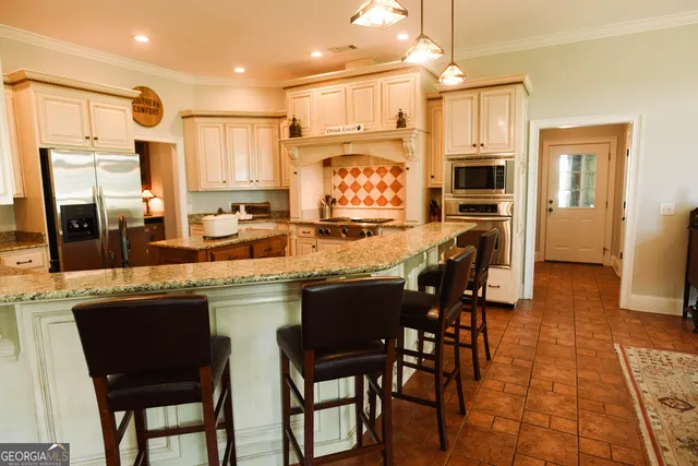 a kitchen with stainless steel appliances granite countertop a table chairs sink refrigerator and microwave
