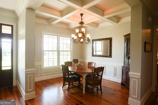 a dining room with wooden floor a chandelier a wooden table and chairs