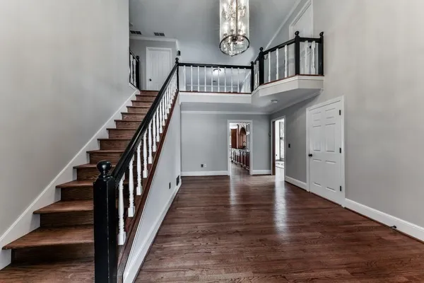 wooden floor with a staircase and view of an entryway with wooden floor