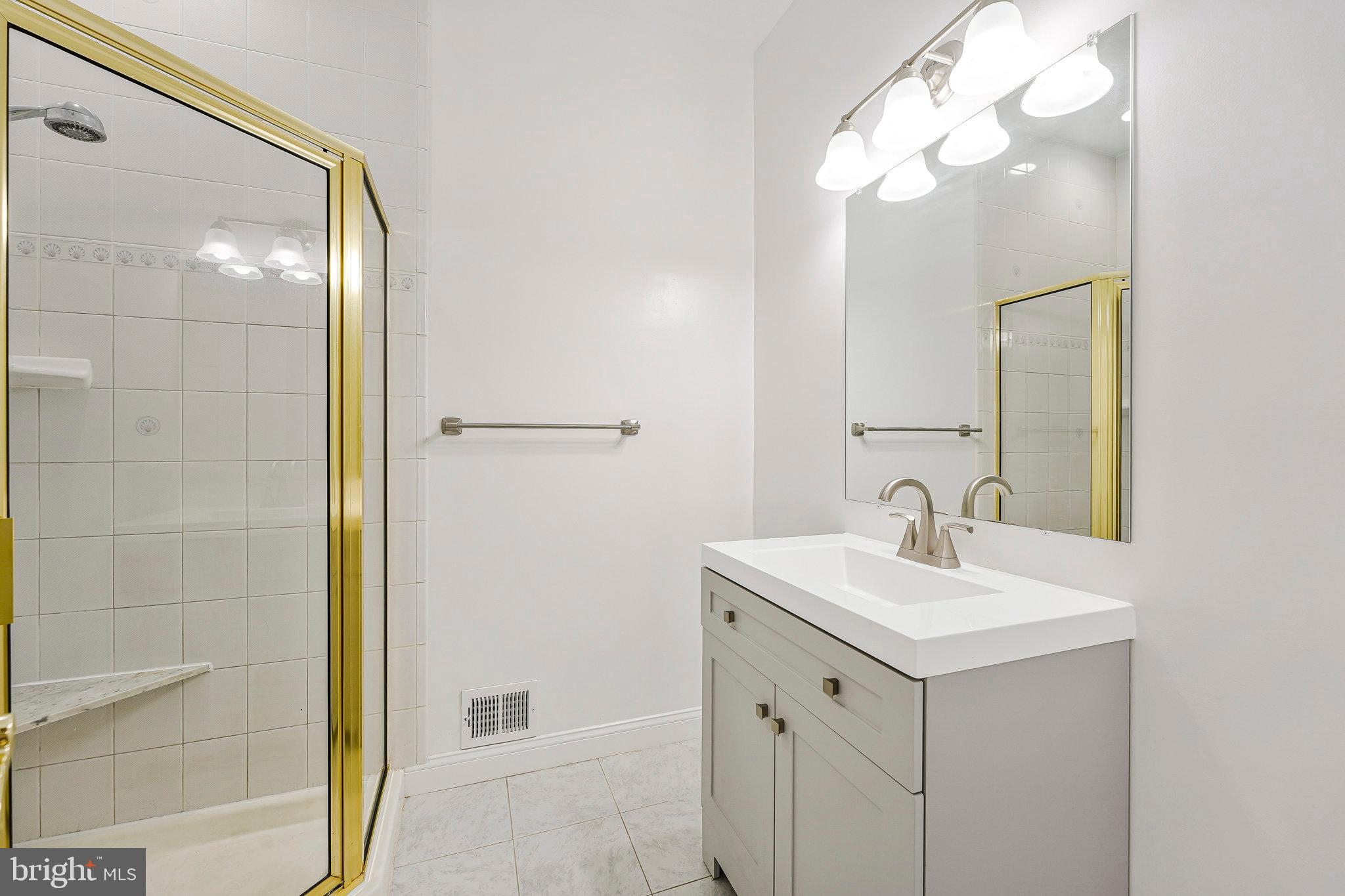 8652 Tuttle Road Springfield, VA 22152 - Photo 39 of 102 a bathroom with a sink a mirror a vanity and a shower