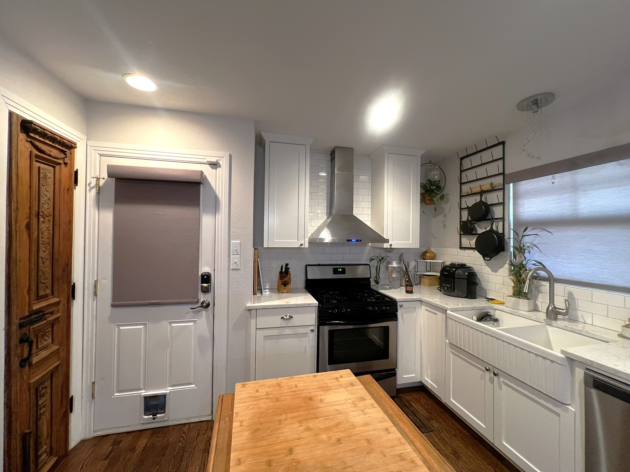 1311 Aggie Lane, Unit A Austin, TX 78757 - Photo 5 of 13 Kitchen with wall chimney exhaust hood, stainless steel appliances, decorative backsplash, and white cabinets