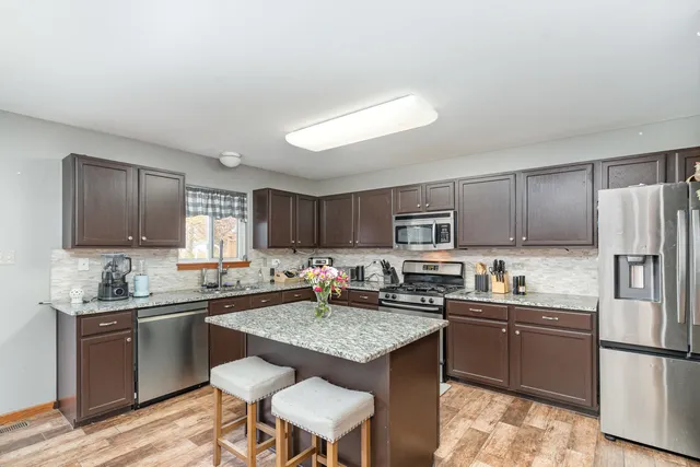 a kitchen with stainless steel appliances granite countertop a sink stove refrigerator and cabinets