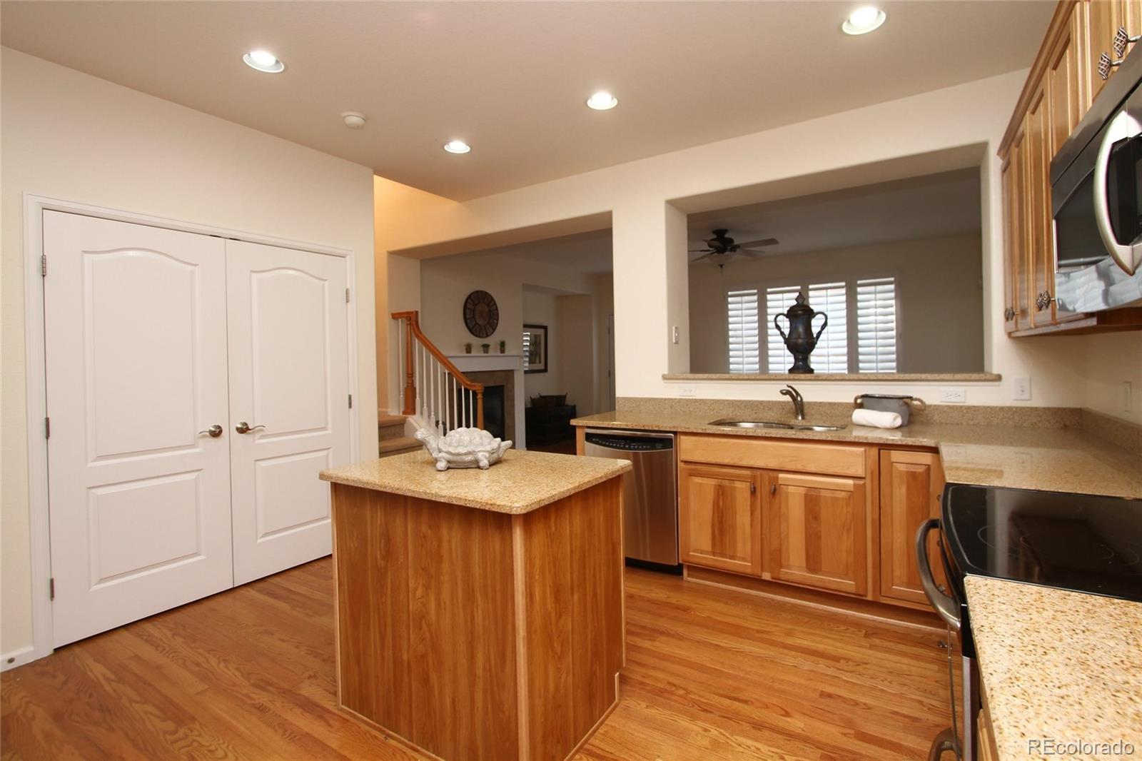 9489 Cedarhurst Lane, Unit B Highlands Ranch, CO 80129 - Photo 9 of 20 a kitchen with kitchen island granite countertop a sink and wooden cabinets